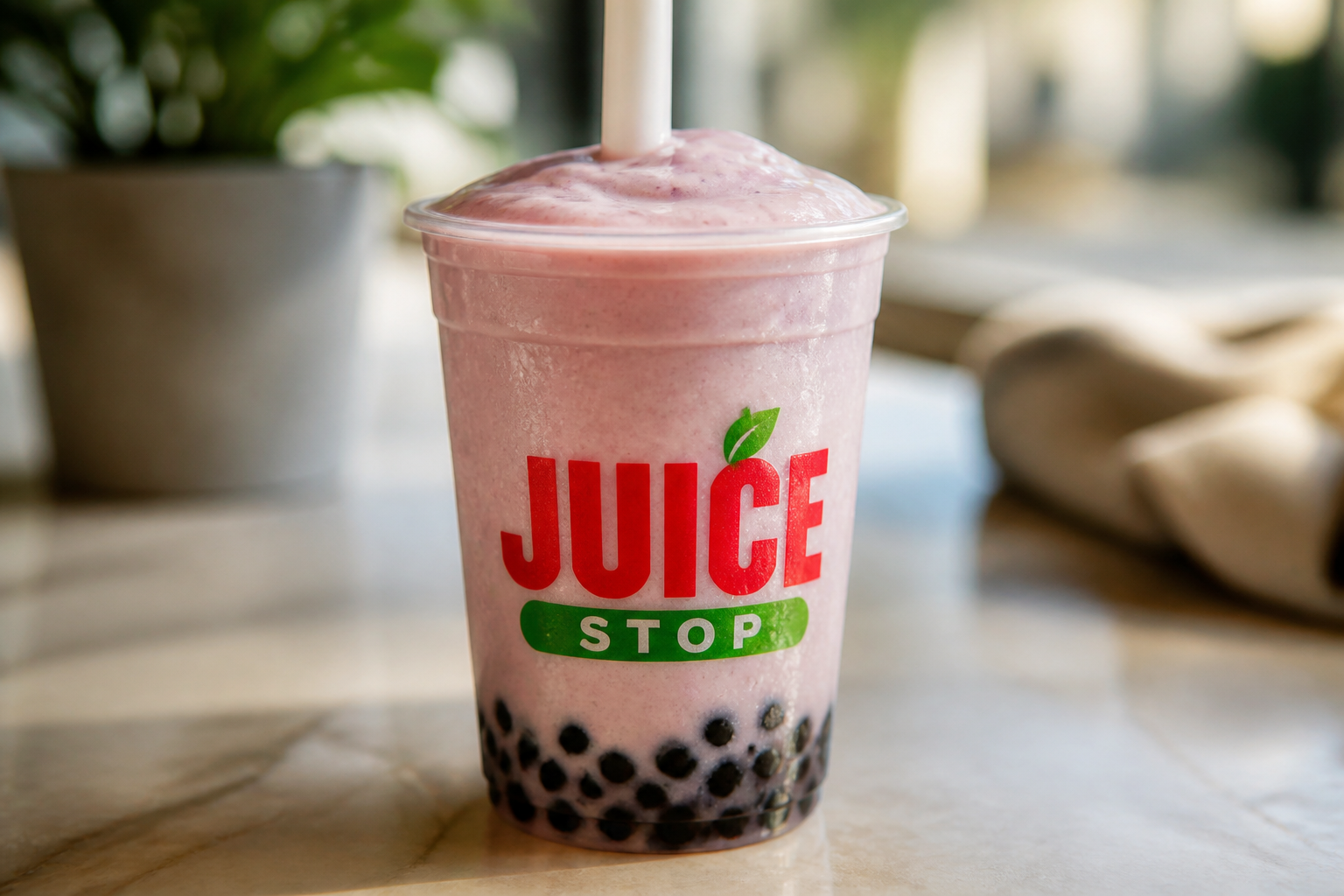 Close-up of a fruit smoothie boba blender with a wide straw and dark tapioca pearls at the bottom of the cup.